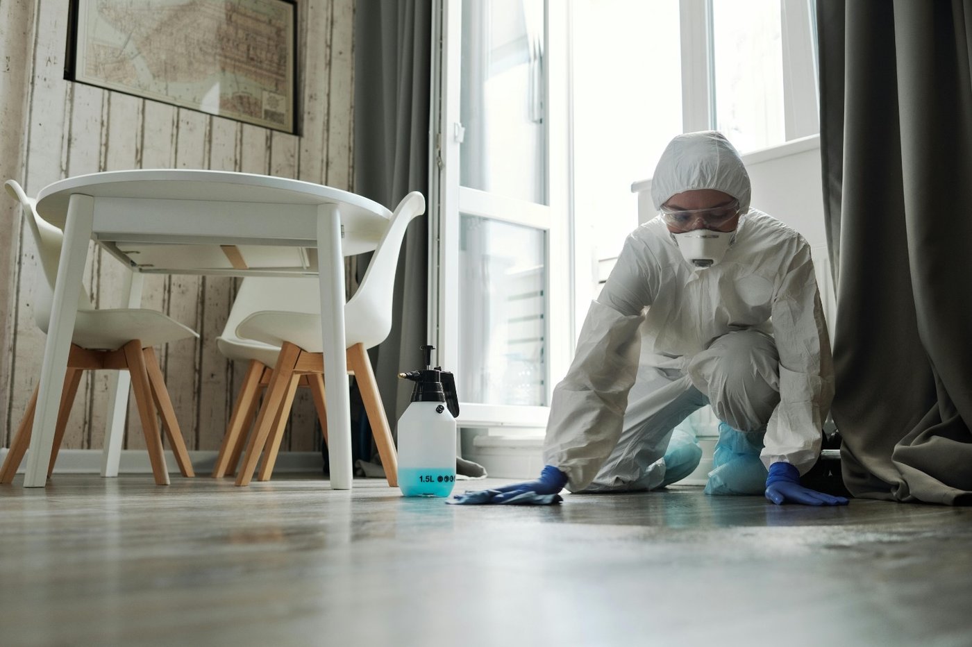 Technician in full PPE assessing and cleaning a floor